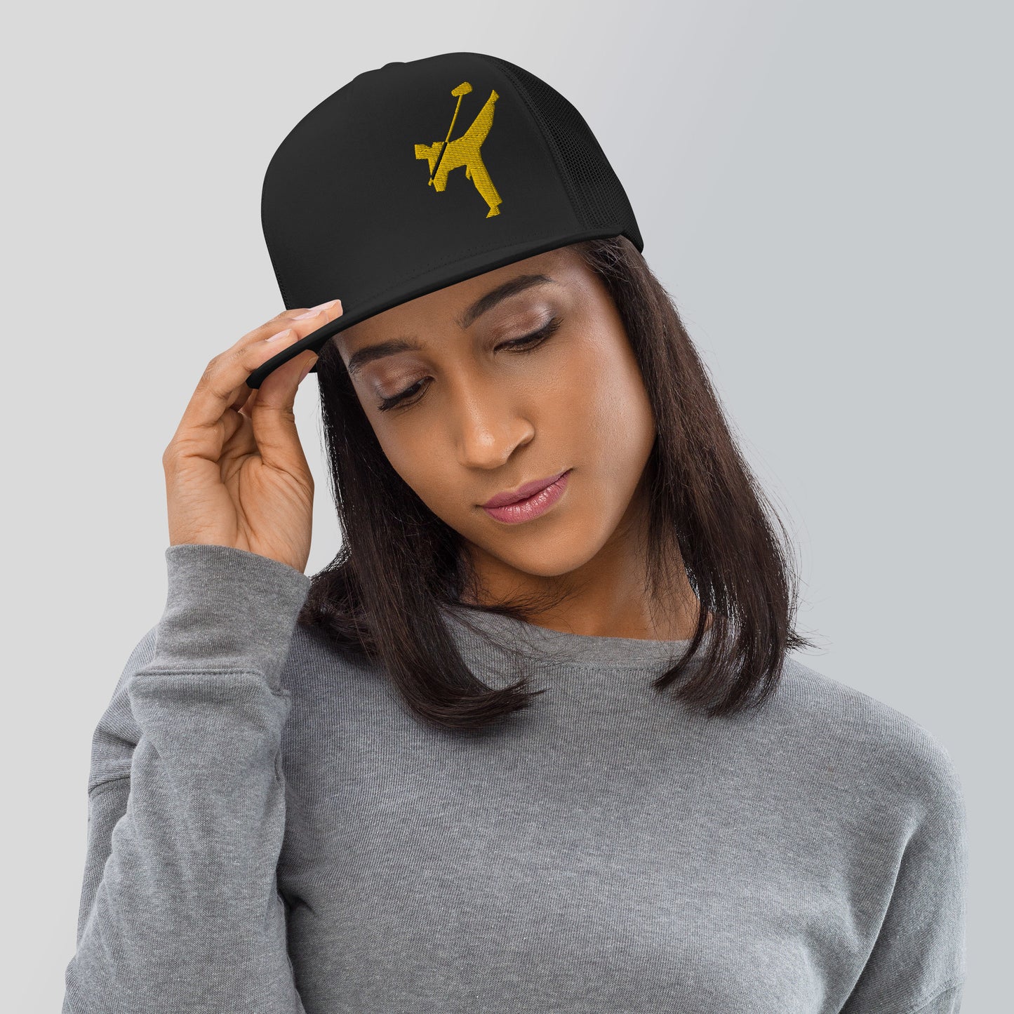 Art Form Gold Boom operator Mesh Snapback Cap. Front view of a woman wearing a black cap with a gold colour graphic of a martial arts fighter, kicking up into the air, holding a boom microphone.