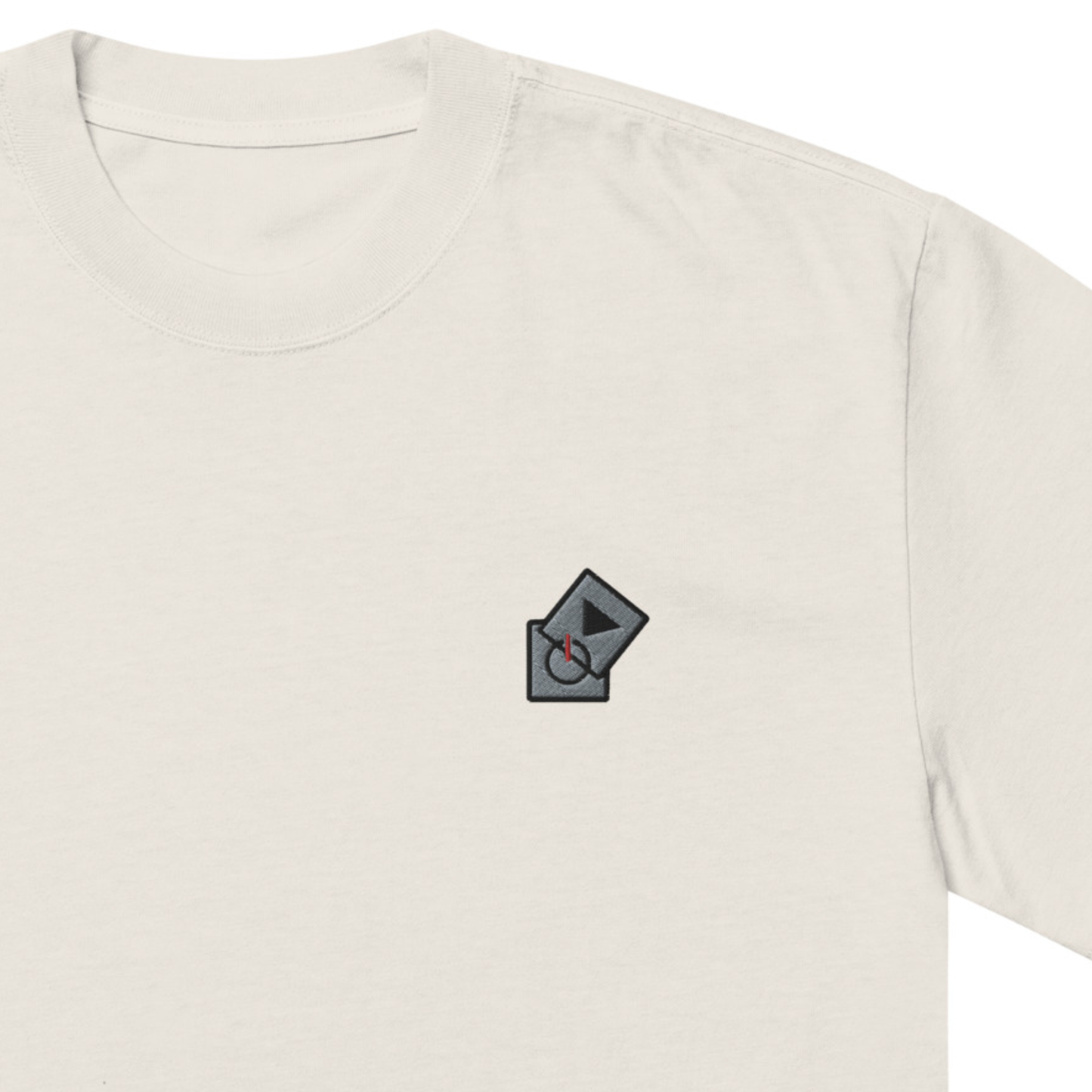 Power Play Audio Icons box fit t-shirt. Close up front view of a bone colour t-shirt with an embroidered graphic of tech icons for power and play in the top left position.