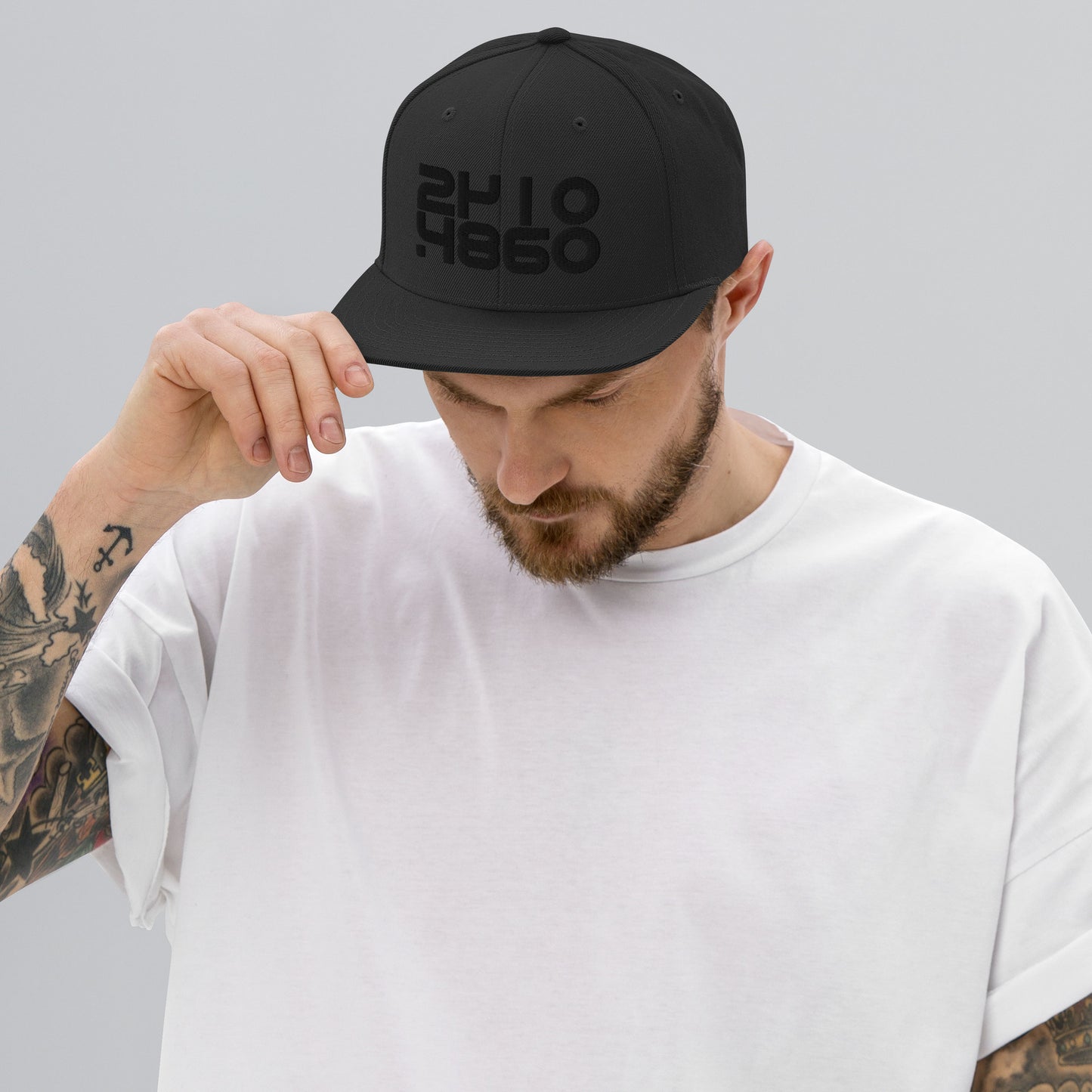 Audio Code classic snapback cap. Front view of man wearing a black snapback cap with embroidered numbers of 16, 24 and 48