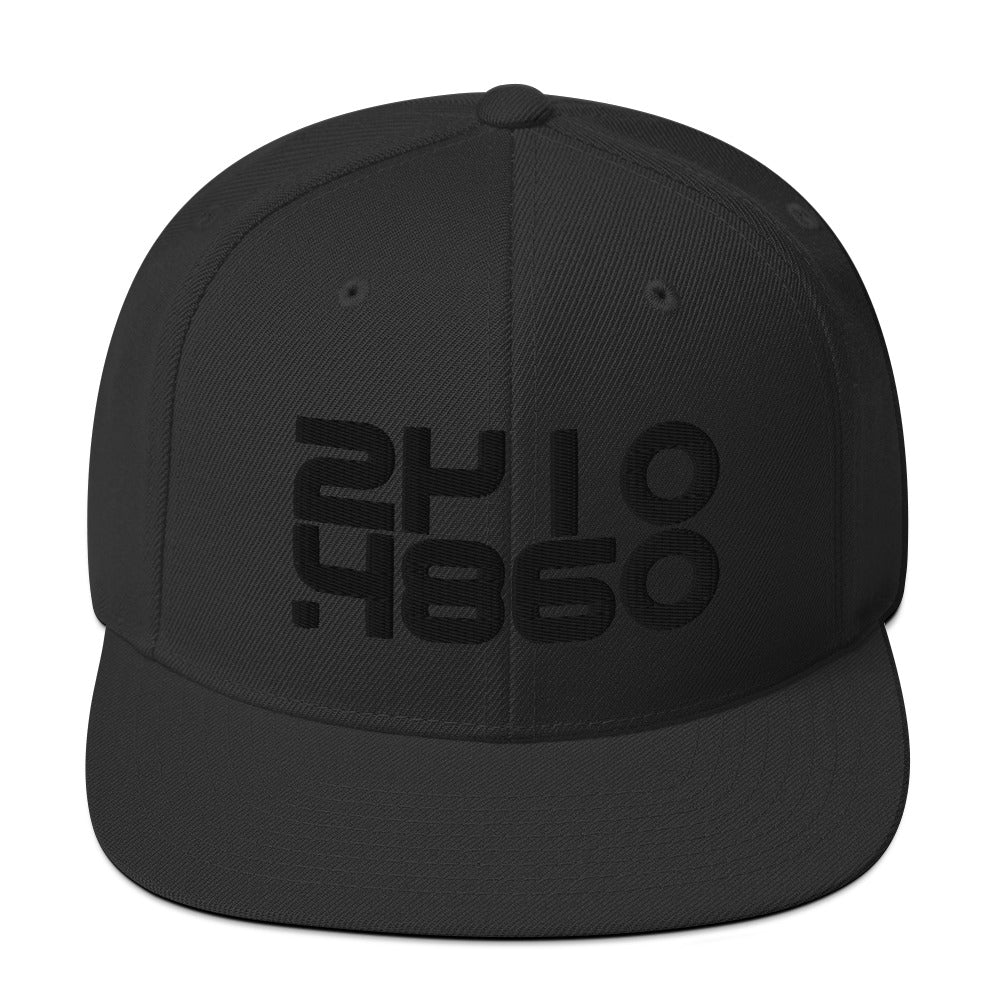 Audio Code classic snapback cap. Close up front view of black snapback cap with embroidered numbers 24, 48 and 16.