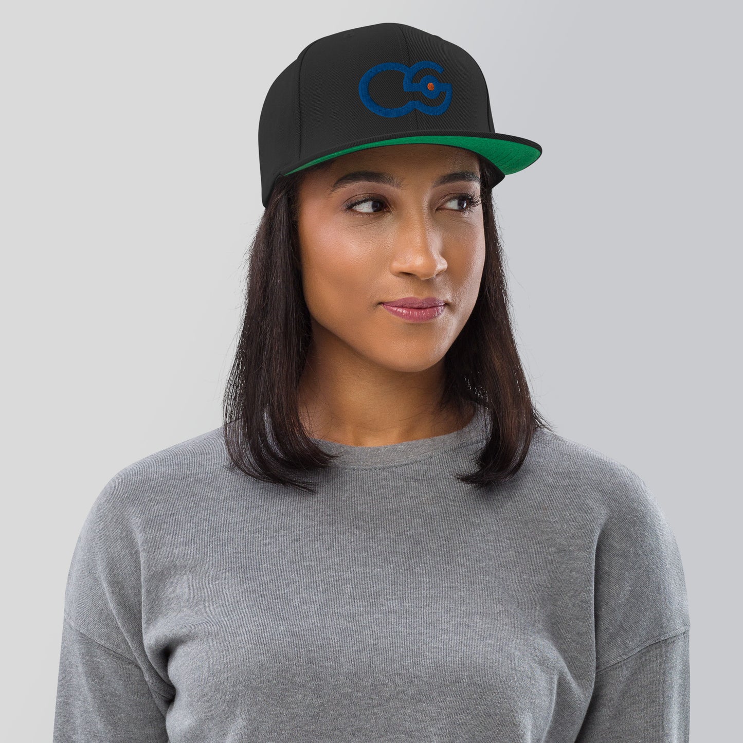 Crew Show logo snapback cap. Front view of woman wearing a black snapback cap with the Crew Show logo embroidered on it.