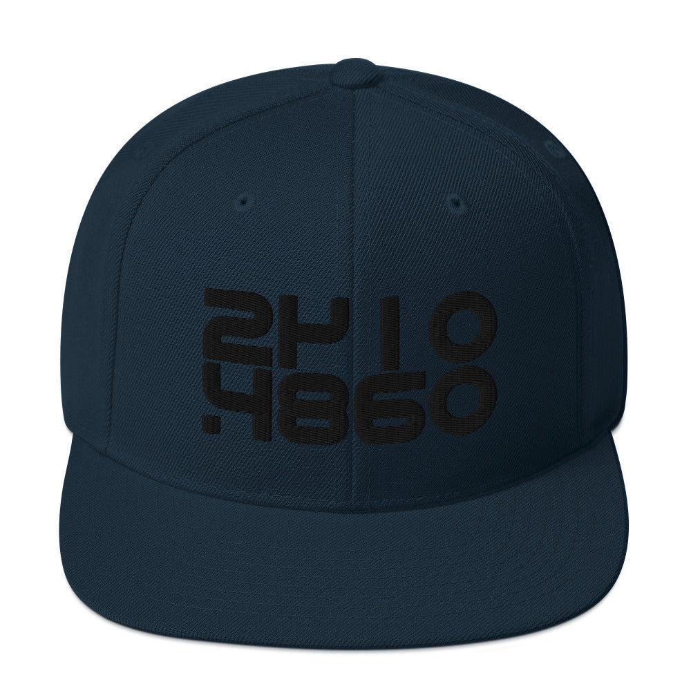 Audio Code classic snapback cap. Close up front view of navy blue snapback cap with embroidered numbers 24, 48 and 16.