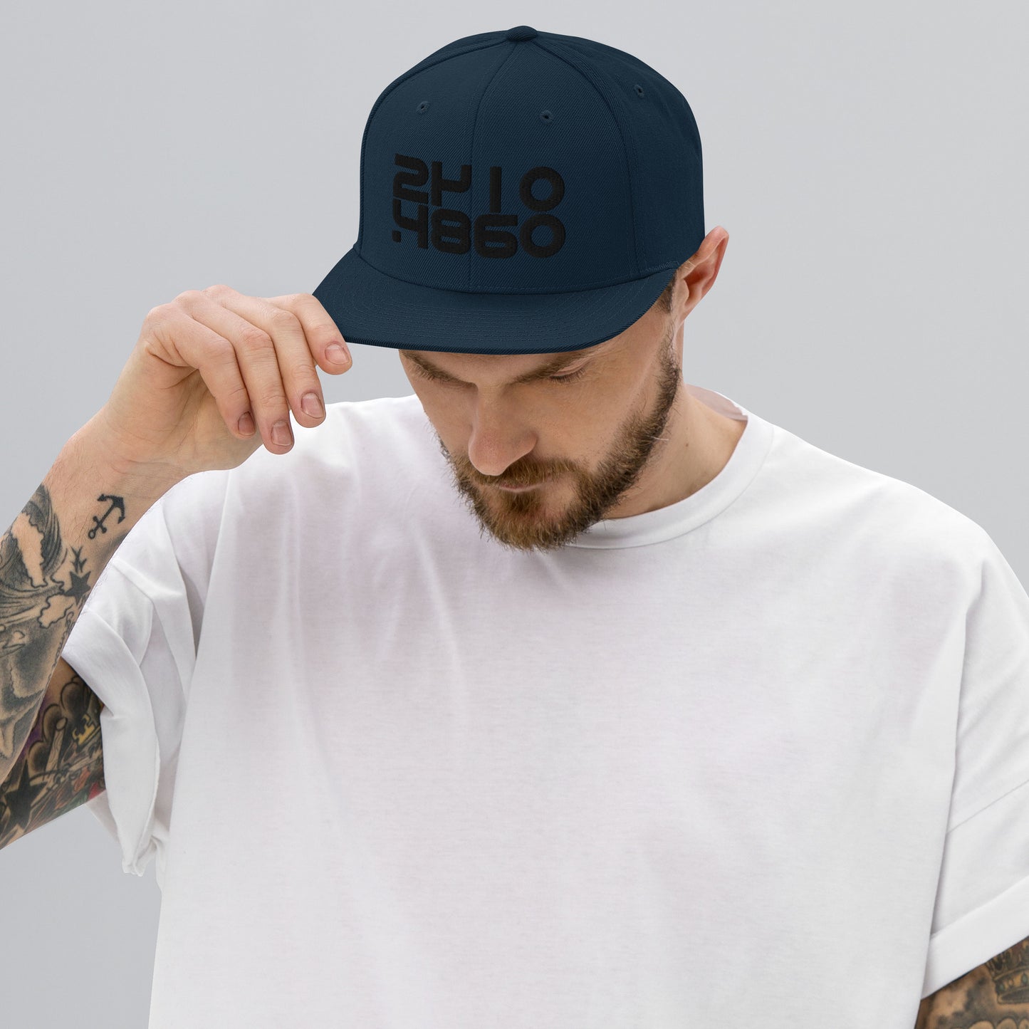 Audio Code classic snapback cap. Front view of man wearing dark navy snapback cap with embroidered numbers of 16, 24 and 48.