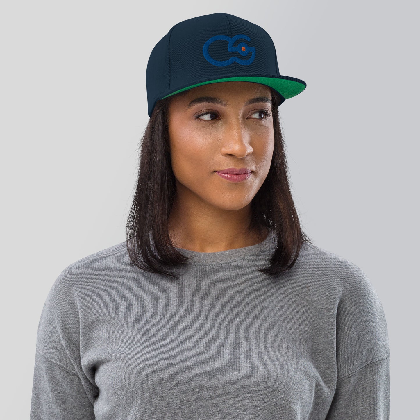 Crew Show logo snapback cap. Front view of woman wearing a dark navy snapback cap with the Crew Show logo embroidered on it.